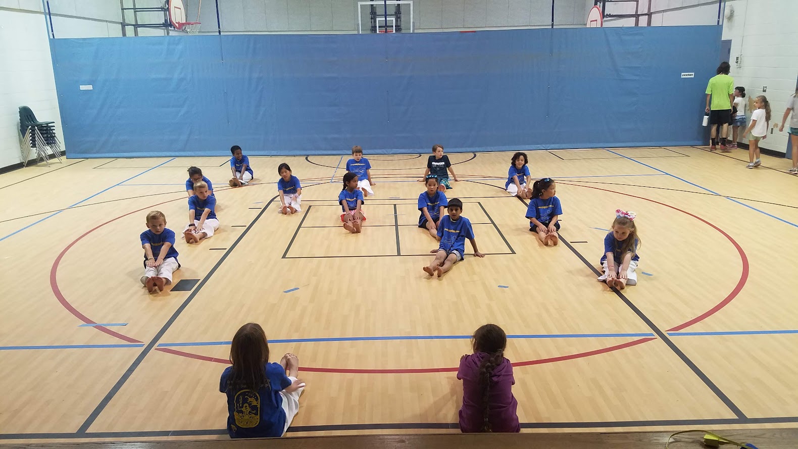 Kids stretching touching toes in gym