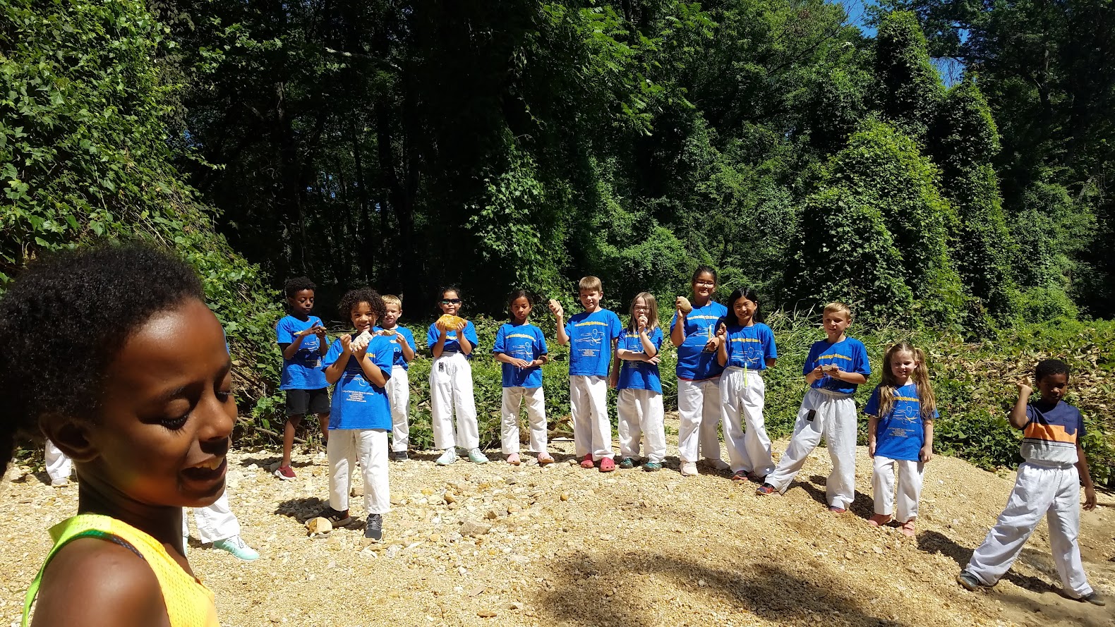 Kids clapping by creek in blue shirts